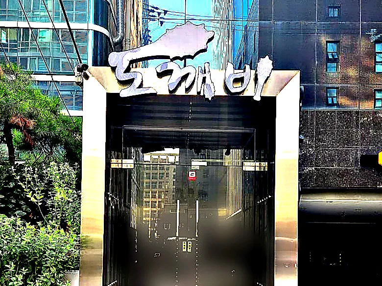 강남 도깨비 간판이 올려진 스테인리스 출입구를 낮에 촬영한 사진