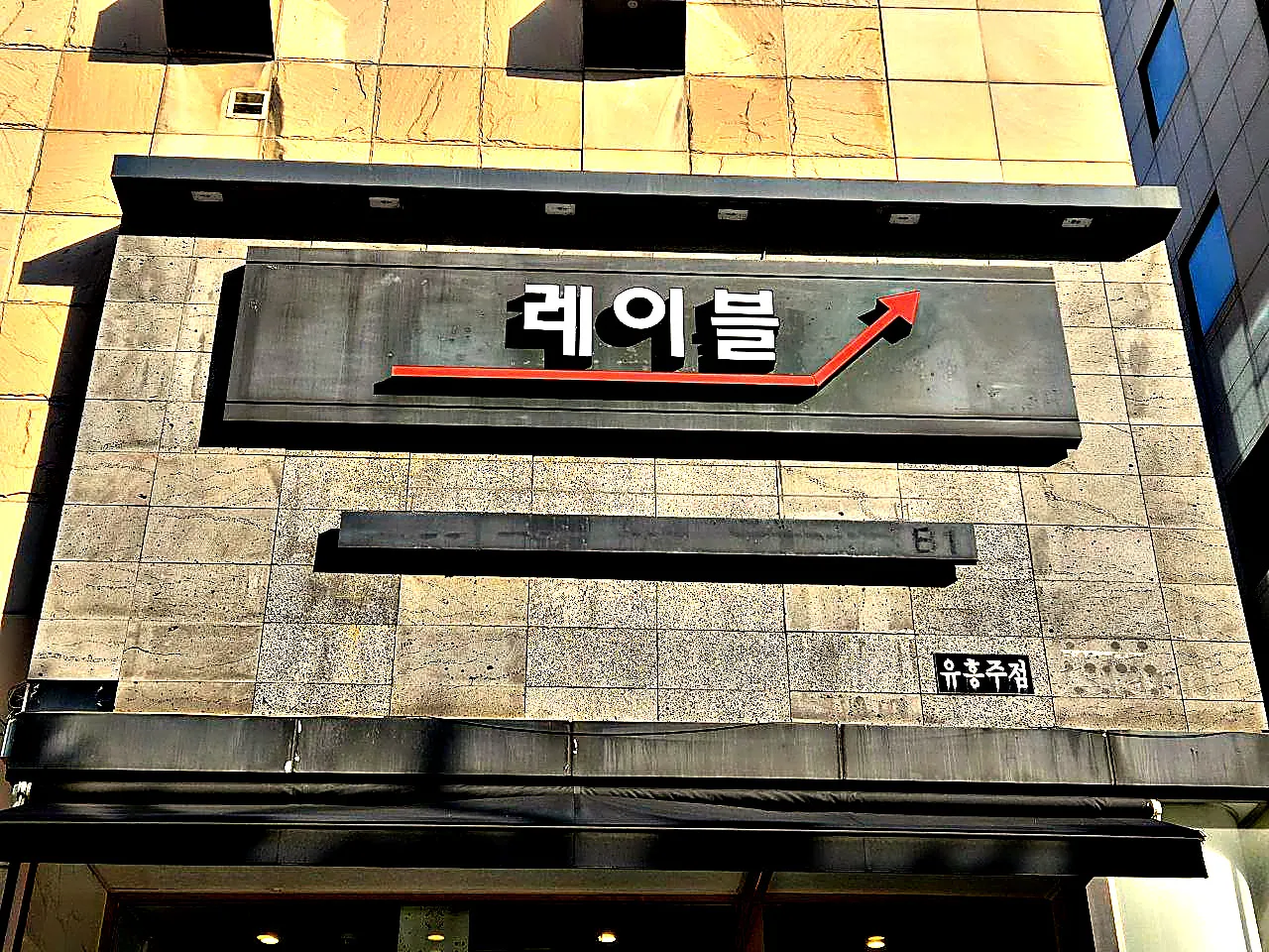 붉은 화살표와 함께 레이블이라고 쓴 강남 레이블 간판을 가까이 올려다본 사진
