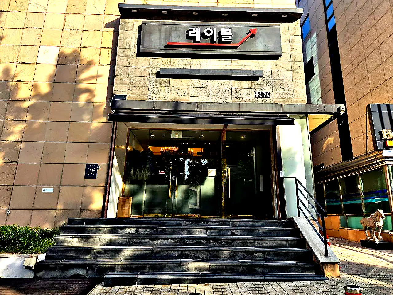 강남 레이블 간판과 유리 출입구, 계단이 함께 보이는 건물 정면 사진