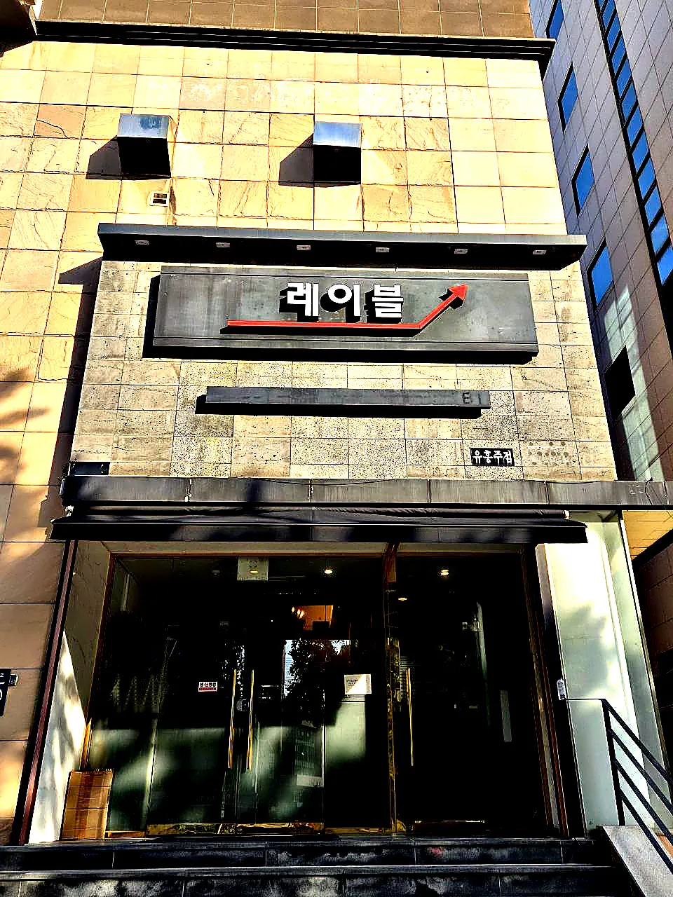 강남 레이블 간판 아래 유리 출입구를 정면에서 촬영한 사진