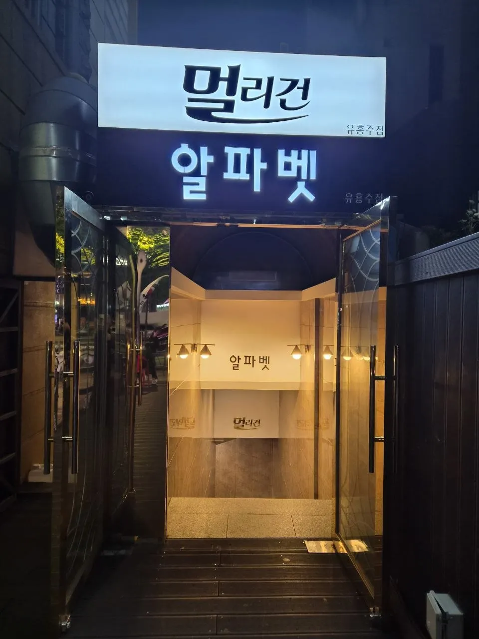 강남 멀리건 간판을 가까이에서 올려다본 사진. 출입구와 바닥까지 함께 보인다