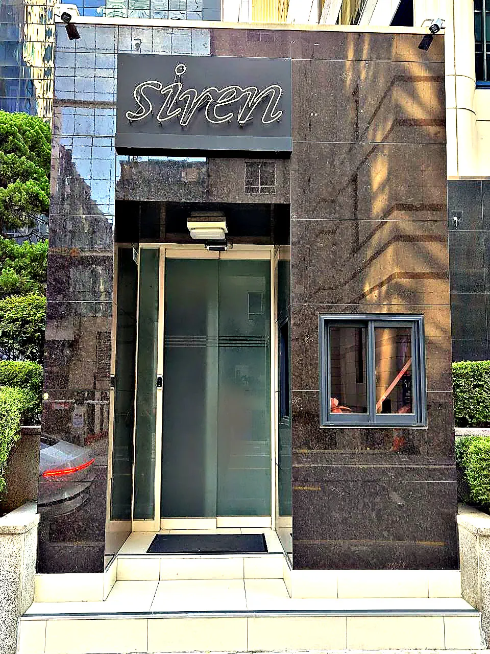 강남 세이렌(siren) 간판 아래 유리 자동문 출입구를 정면에서 촬영한 사진