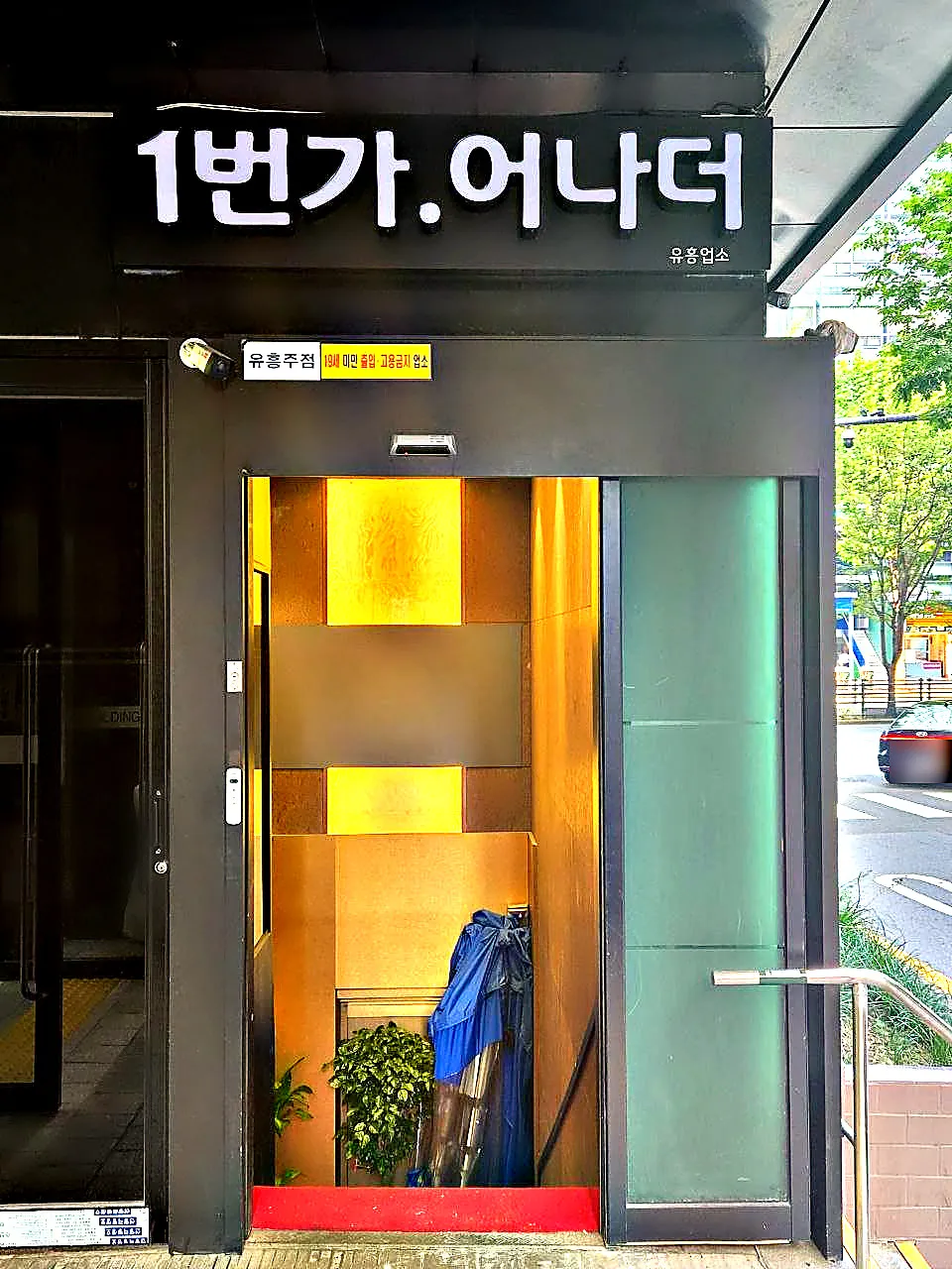 강남 어나더(1번가 어나더) 간판이 달린 건물 출입구를 정면에서 촬영한 사진