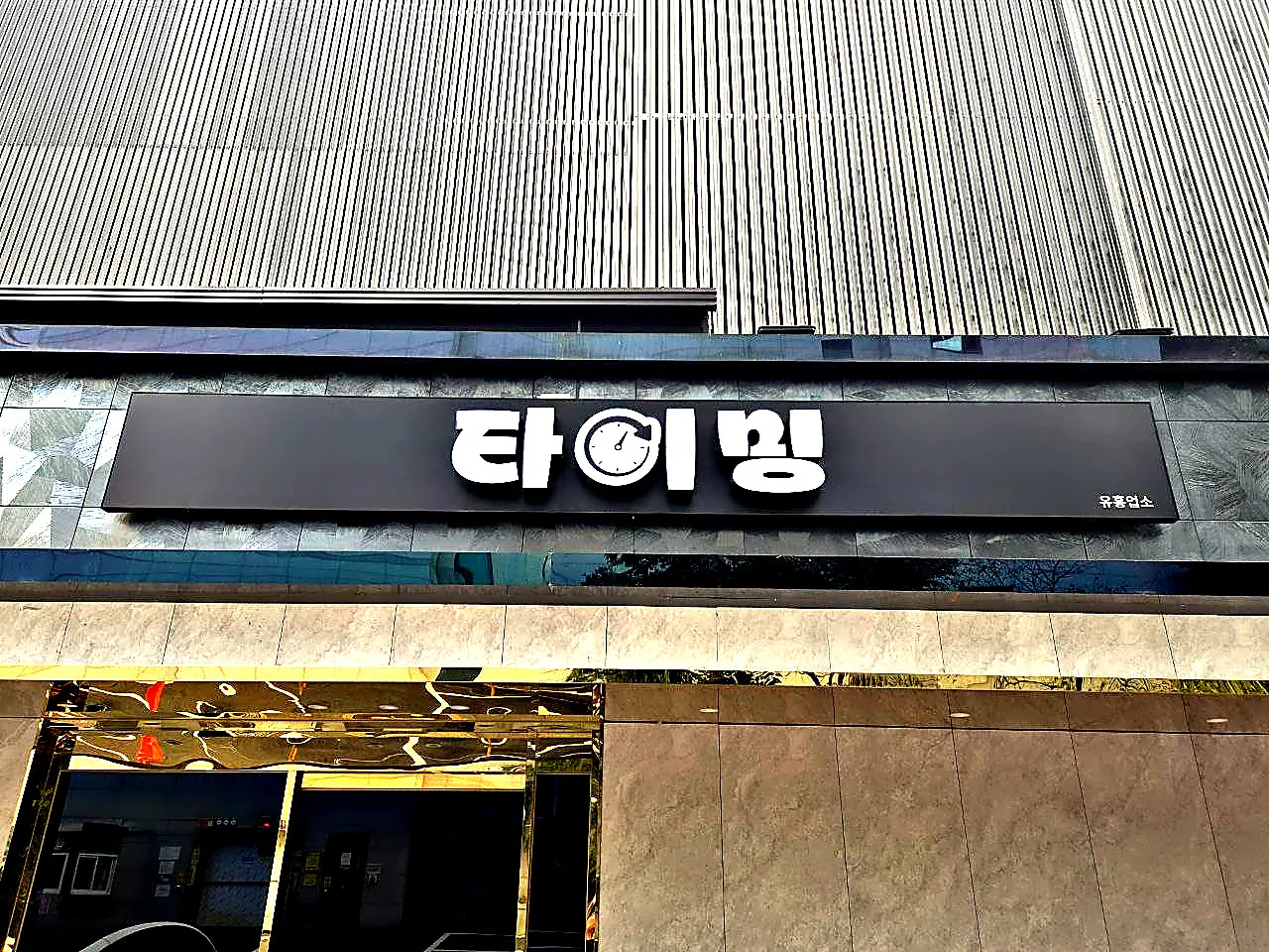 시계 그림이 들어간 강남 타이밍 간판을 가까이 올려다본 사진