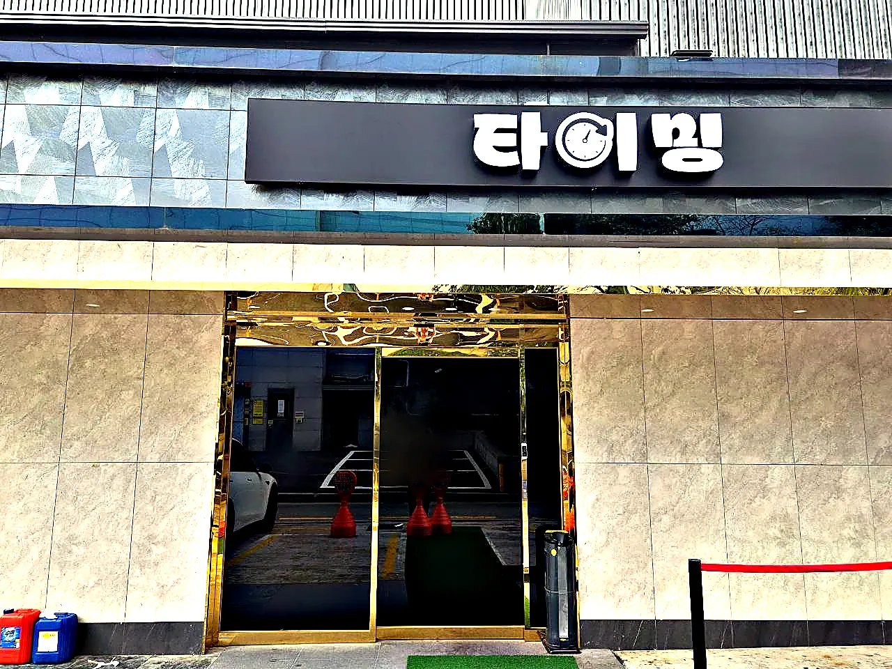 강남 타이밍 간판과 금색 테두리 유리 출입구가 함께 보이는 건물 앞 사진